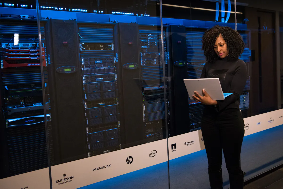 Illustration d'une technicienne consultant une tablette devant une baie de serveurs dans un data center
