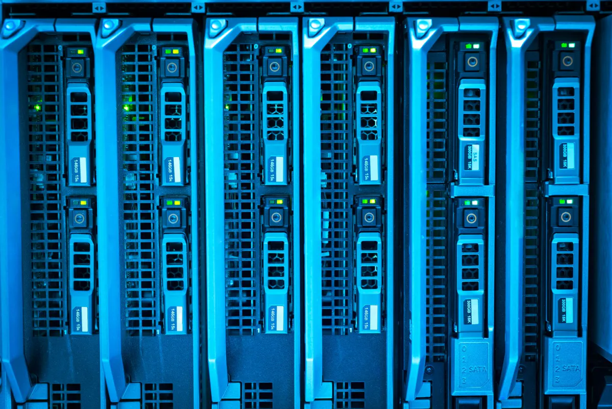 Gros plan sur des baies de disques durs empilées dans un rack serveur éclairé en bleu