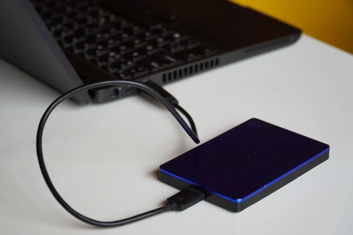 External hard drive connected by USB cable to a laptop sitting on a desk, illustration