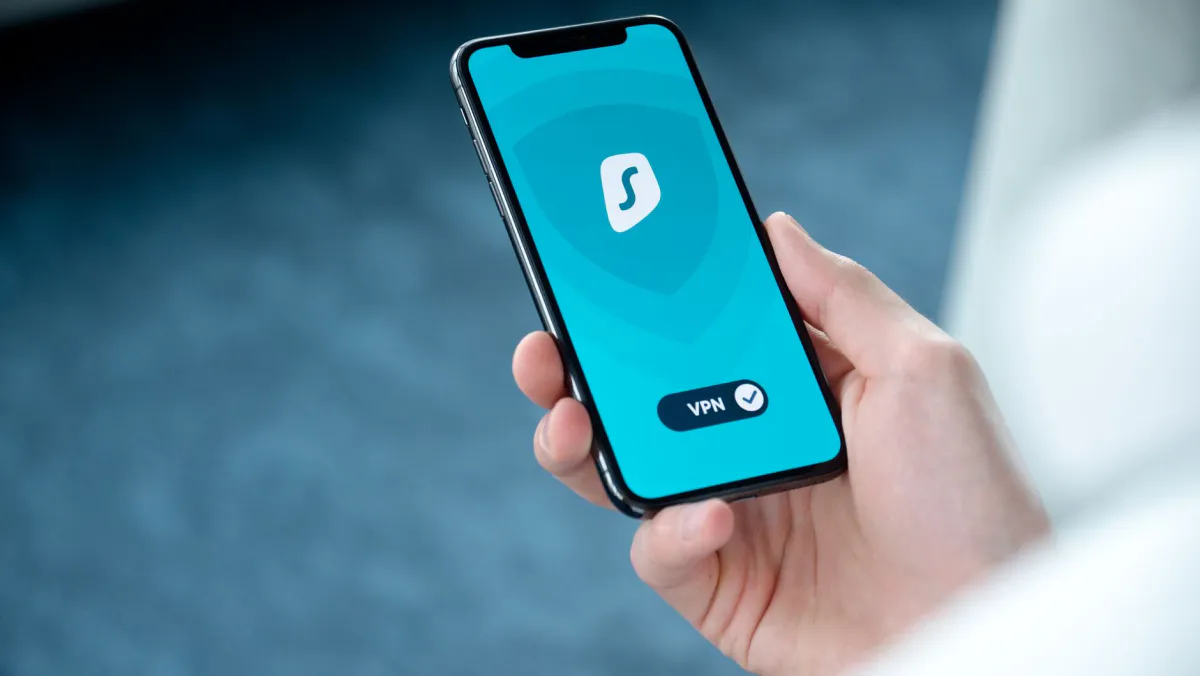 Hand holding a smartphone showing an active VPN app, with a checked VPN toggle at the bottom of the screen