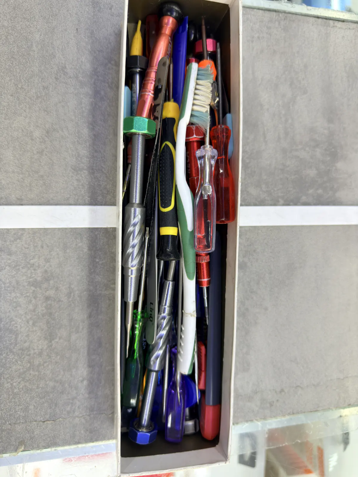 Close-up of spudgers, an anti-static brush and precision screwdrivers stored upright in a RELIFE toolbox