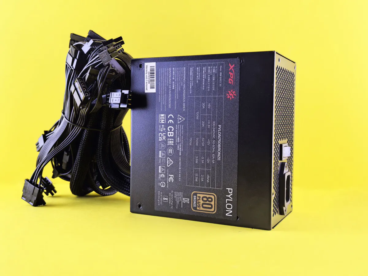 Black PC power supply unit on a yellow background, with detached modular cables next to it