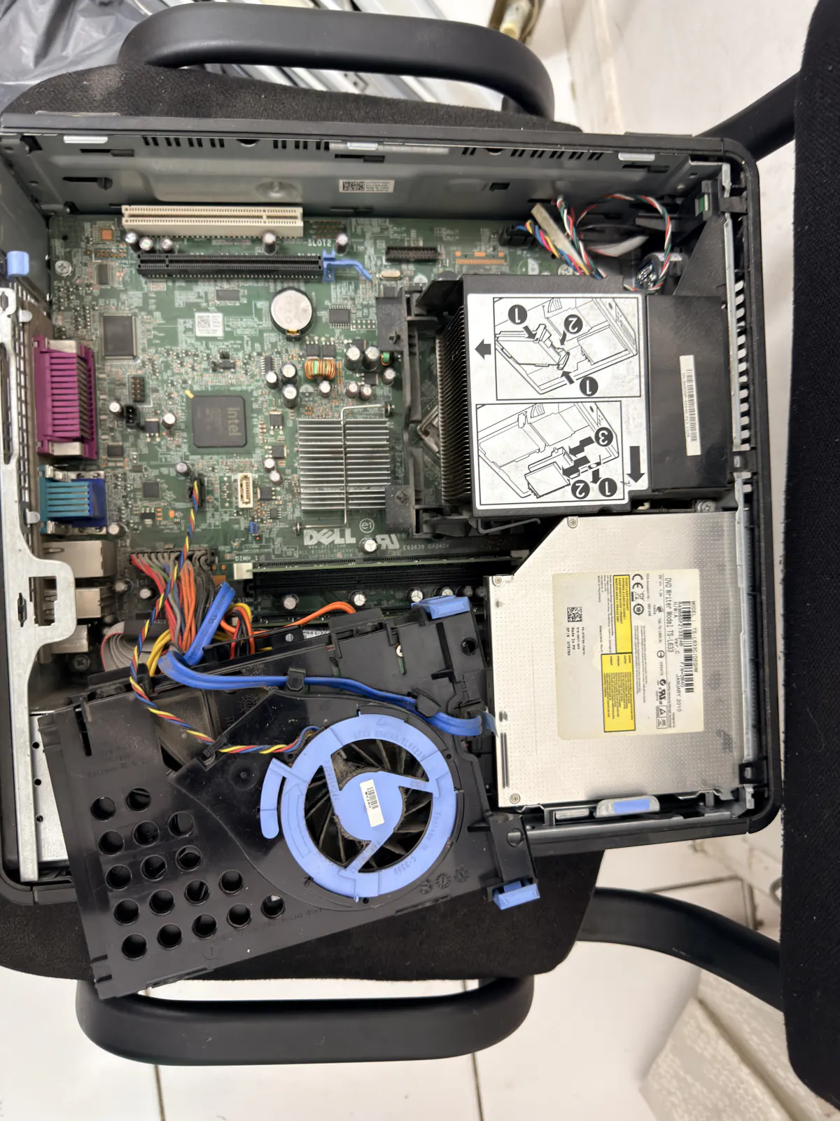 Interior of an open Dell desktop tower in the workshop, motherboard and DVD drive visible before diagnosis