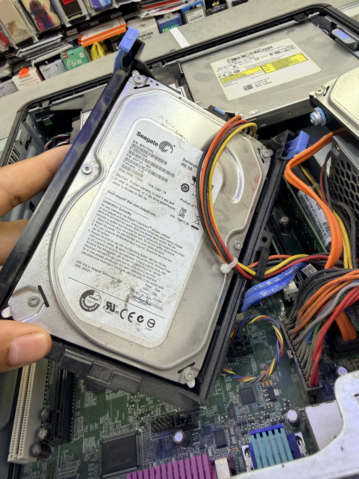 Removing a Seagate Barracuda 250GB hard drive from an open desktop tower, power and data cables still attached